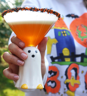 Woman wearing a Halloween sweater holding a Candy Corn Martini in a ghost cup