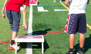 Two boys playing cornhole on a football field