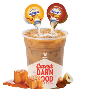 Cup of iced coffee with hazelnut and caramel macchiato creamer being poured in.