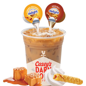 Cup of iced coffee with hazelnut and caramel macchiato creamer being poured in.