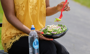 A woman eating a Casey's salad on a park bench