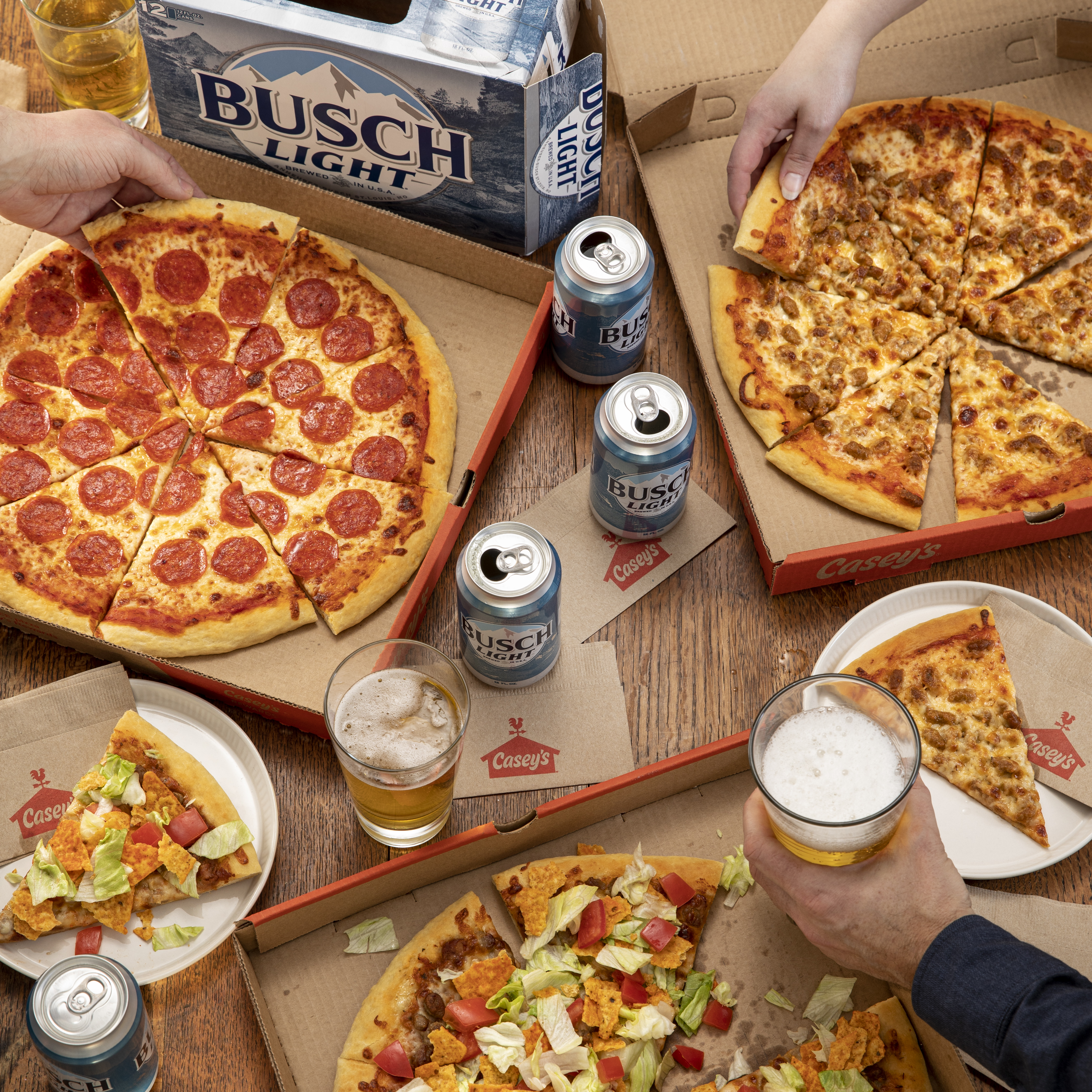 Busch Light, Casey's Pepperoni Pizza, Taco Pizza, and Sausage Pizza on a table