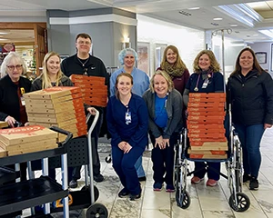 group of people with 4 stacks of casey's pizza boxes