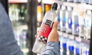 Someone holding a bottle of LIFE WTR in front of a fridge of waters