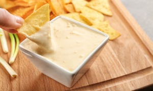 Someone dipping a tortilla chip into Beer Cheese Dip