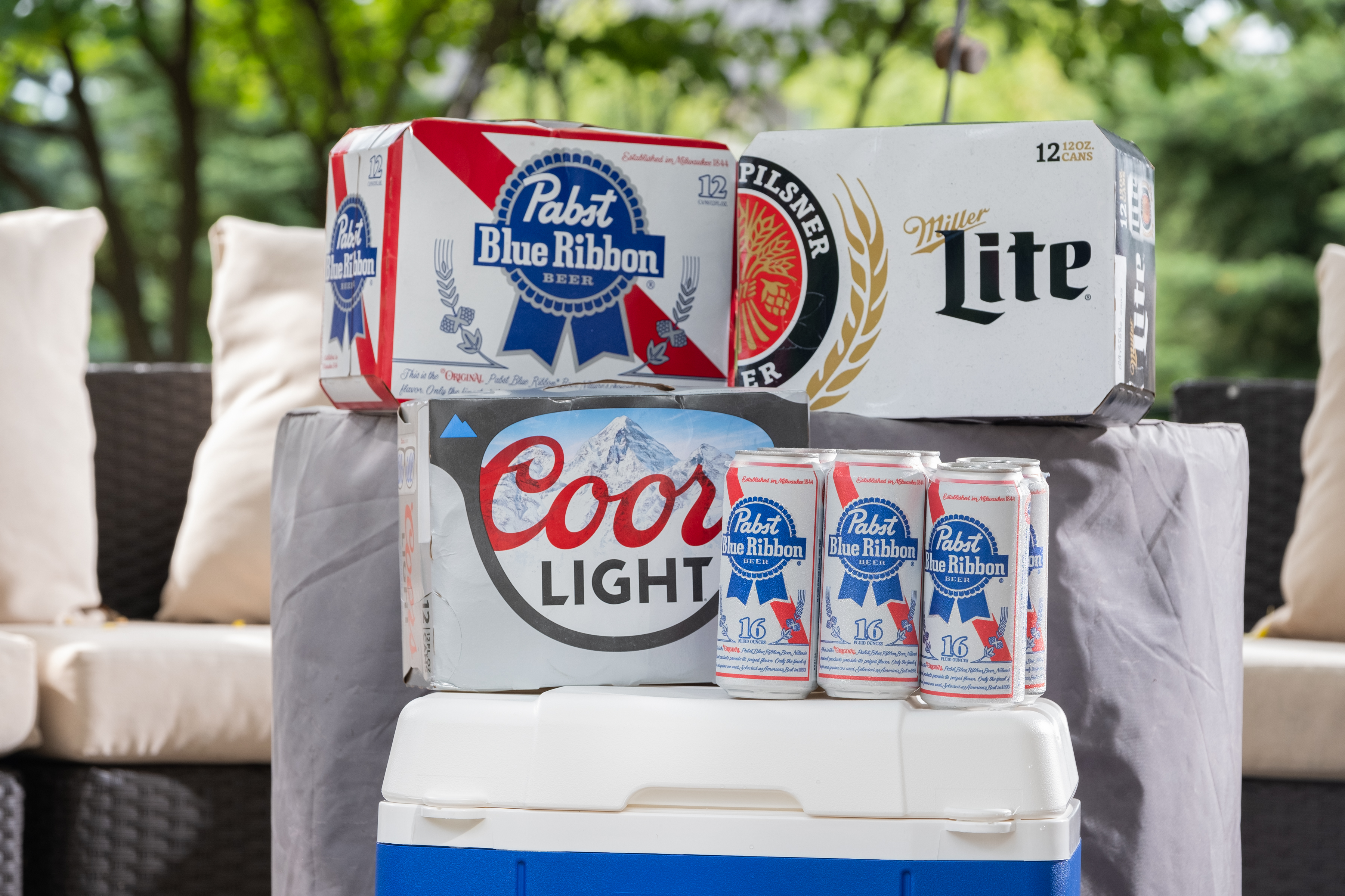 Packs of Pabst Blue Ribbon, Coors Light, and Miller Lite on a cooler