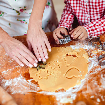 child and parent rolling out cookie dough