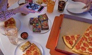 Girl takes a picture of her Casey's pizza, breadsticks, and Party Brookie