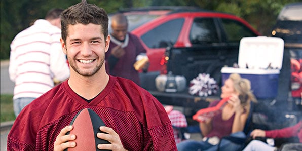 Man with football at a tailgate with friends